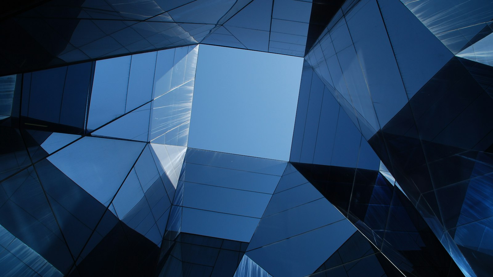 Abstrakte blaue Glasfassade mit geometrischen Facetten von unten fotografiert